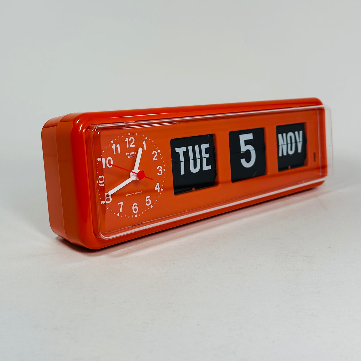 Retro orange analog clock with clock face and vintage mechanical flip date, mid-century modern desk or wall clock